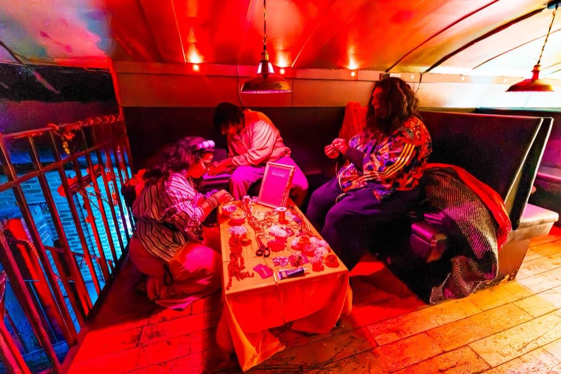 A craft table under red light, people making parandi