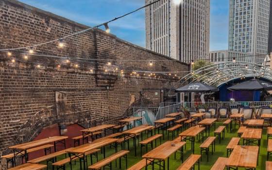 The rooftop terrace — bench tables under festoon lights
