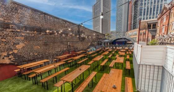 The open-air rooftop terrace, bench tables under festoon lights