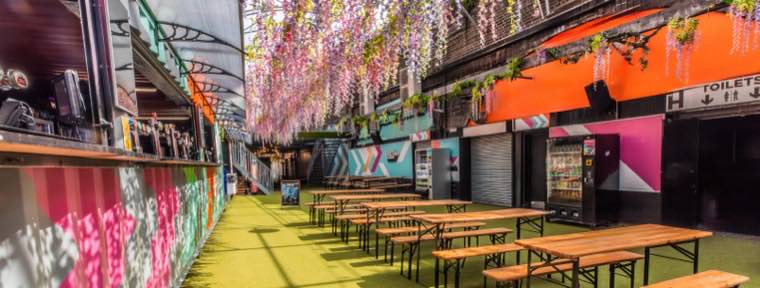 Covered walkway hung with blossom, lined with benches and food traders