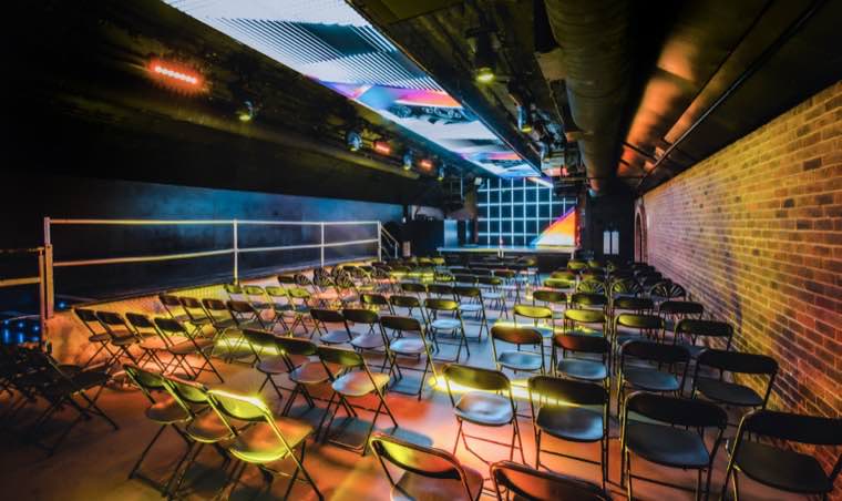 Warmly lit brick arch with rows of chairs facing a stage
